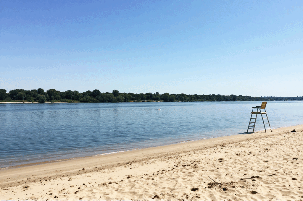 A sandy river beach with a lifeguard chair on a clear summer day.